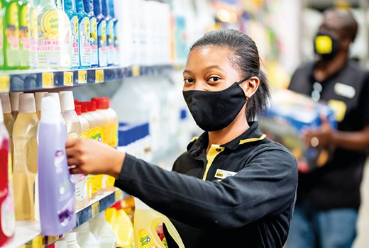 An associate wearing a protective face mask stocks a shelf.