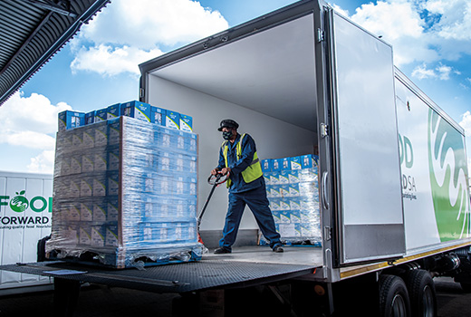 A worker unloads food donations from the back of a large truck.