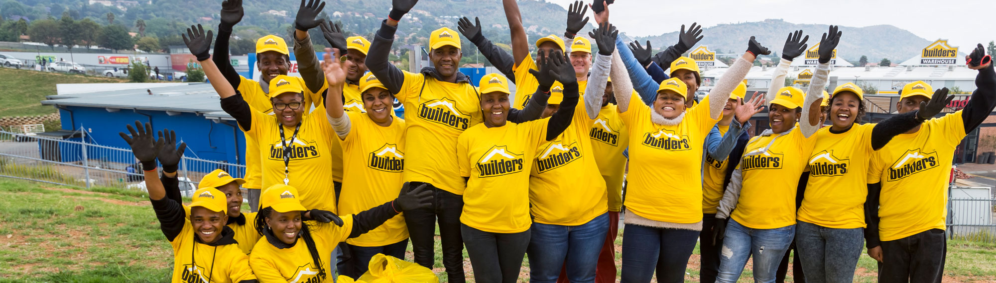 Builders associates celebrate outside a store, joyfully reaching their arms up in the air.